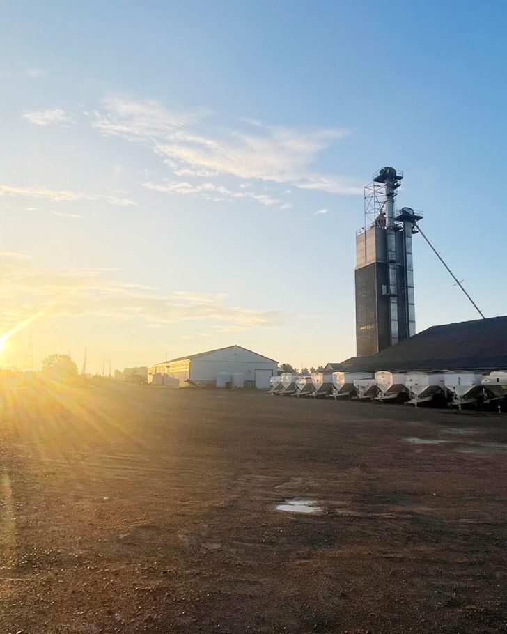 Holmes Agro lot with farming equipment and sunset in the background