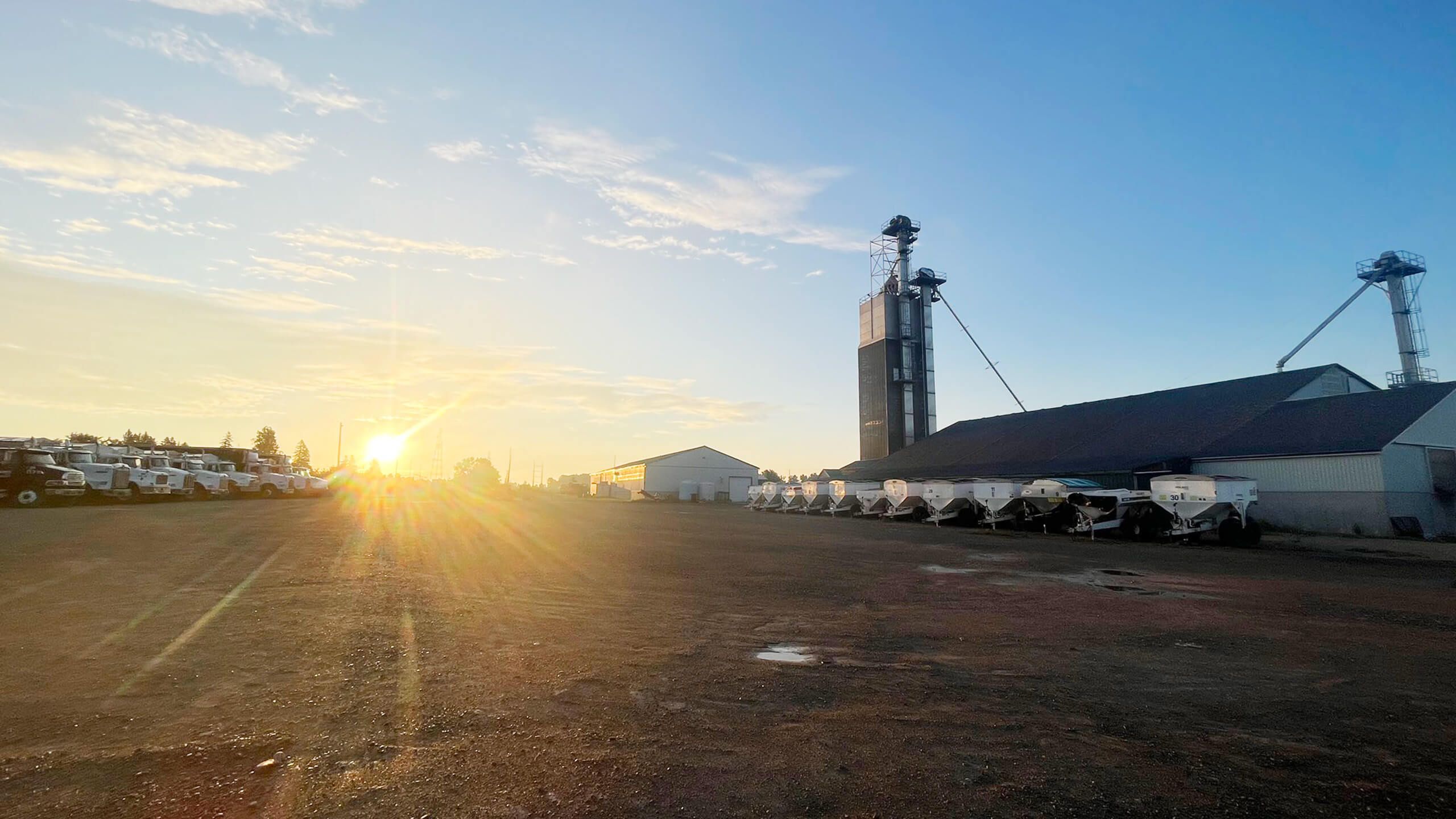Holmes Agro lot with farming equipment and sunset in the background